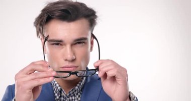 Mavi ceketli havalı adam gözlük takıyor, beyaz arka planda kendine güvenen bir şekilde poz veriyor.