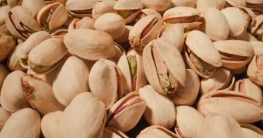 Makro manzaralı şam fıstığı yığını. Doğal çatlamış kabuklarını ve canlı yeşil iç kısımlarını vurguluyorlar.