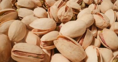 Antep fıstıklarının yakın çekimi, dokulu kabukların altını çizmek ve cevizlerin zengin, toprak yeşili tonları.