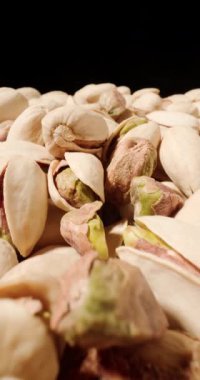 Makro manzaralı şam fıstığı yığını. Doğal çatlamış kabuklarını ve canlı yeşil iç kısımlarını vurguluyorlar.