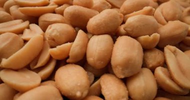 Tuzlu fıstıklardan oluşan makro bir çekim, çıtır çıtır yüzey ve altın kabuklarını narin tuz kristalleri arasında sergiliyor.