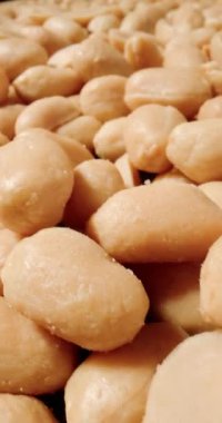 Tuzlu fıstıklardan oluşan makro bir çekim, çıtır çıtır yüzey ve altın kabuklarını narin tuz kristalleri arasında sergiliyor.