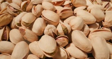 Antep fıstığı makro pozu, kremsi bej kabuklarını sergiliyorlar canlı yeşil çekirdekler içinden gözetliyor.