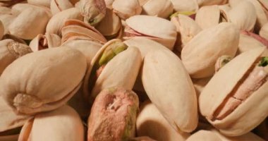 Pürüzsüz bej kabukları ve içindeki taze yeşil çekirdekleri içeren şam fıstıklarının detaylı bir çekimi.