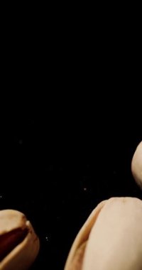 Sağlıklı yağ ve enerji artışı kaynağı olarak sağlıklı atıştırmalıklar için kullanılan bir grup kabuklu yeşil şam fıstığı siyah arkaplanın önüne düşüyor.