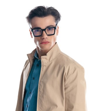 Gözlüklü ve beyaz arka planda poz veren kendinden emin genç bir adam.