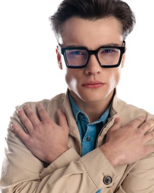 Gözlüklü, el ele tutuşan ve beyaz arka planda poz veren çekici bir gencin portresi.