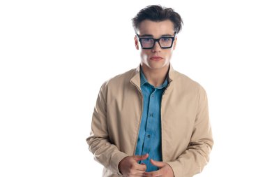 Siyah gözlüklü sıradan bir genç, parmaklarına dokunuyor ve beyaz arka planda ileri bakıyor.