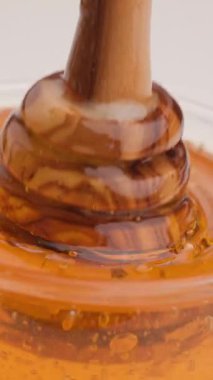 Altın bal, kaşık kavanoza girerken kıvrılır. Yapışkan, pürüzsüz akışını ve organik ışıltısını açığa çıkarır. Yavaşça damlarken.