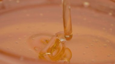 Yapışkan parlak bal, koyu kehribar tonlarında yavaşça akıyor, saf organik tatlılığı yakalıyor.