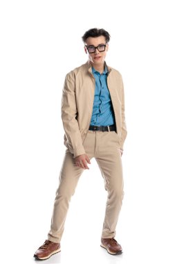 Gözlüklü seksi genç adam beyaz arka planda dururken el ele poz veriyor.