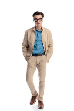 Gözlüklü, el ele tutuşan ve beyaz arka planda yürüyen kendinden emin bir gencin tam vücut resmi.