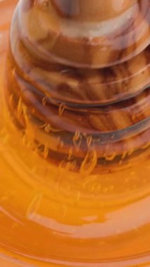Bal kaşığının yavaşça kavanoza batması, yapışkan, altın şurubu pürüzsüz, akışkan bir hareketle karıştırması.