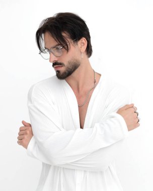 Kollarını kavuşturup beyaz arka planda poz veren sakallı genç adam.