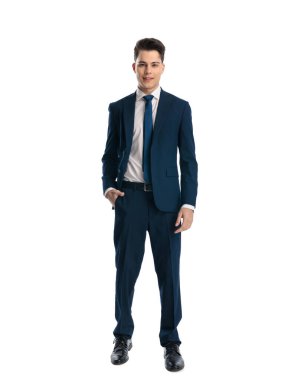 Donanma mavisi takım elbiseli mutlu, zarif bir iş adamının tüm vücudu cebinde duruyor ve beyaz arka planda gülümsüyor.