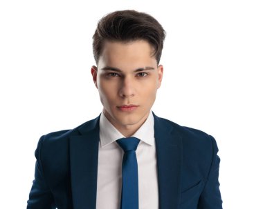 Lacivert takım elbiseli ve kravatlı zarif iş adamının portresi kameraya bakıyor ve beyaz arka planda poz veriyor.