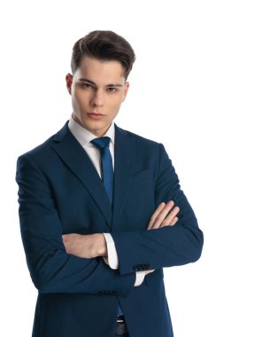 Kravat katlayan kolları olan ve beyaz arka planda rahatça poz veren lacivert takım elbiseli havalı bir adam.