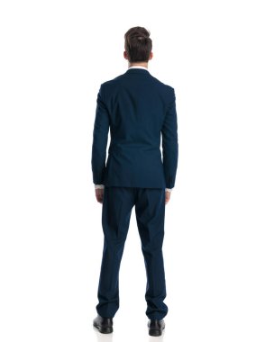 Beyaz arka planda duran lacivert takım elbiseli zarif genç işadamının arkadan görünüşü