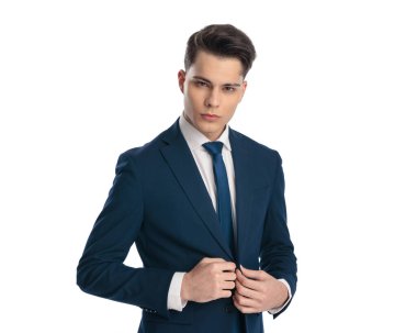 Kendine güvenen zarif iş adamı beyaz arkaplan önünde lacivert takım elbise giymeye can atıyor.