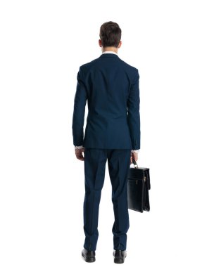 Bavullu lacivert takım elbiseli, beyaz arka planda duran zarif genç adamın arka planı.