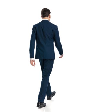 Beyaz arka planda yürüyen lacivert takım elbiseli zarif genç işadamının arka planı.