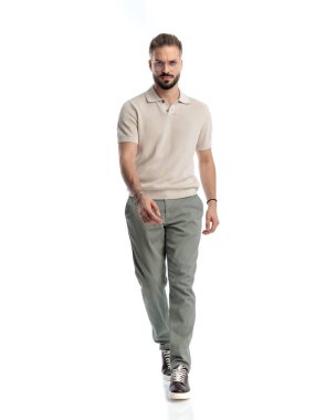 Gözlüklü havalı bir adam ileriye bakıyor ve beyaz arka planda yürüyor. 