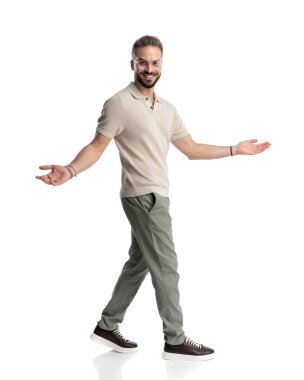 Kollarını açıp gülümseyen ve beyaz arka planda yürüyen gözlüklü sıradan bir genç.