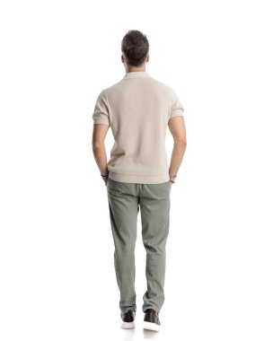 Beyaz arka planda elleri ceplerinde yürüyen genç bir modacının arka planı.