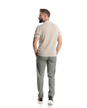 El ele tutuşup beyaz arka planda yürüyen sakallı bir gencin dikiz görüntüsü.