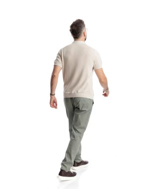 Polo tişörtlü, beyaz arka planda yürüyen sıradan bir gencin arka planı.