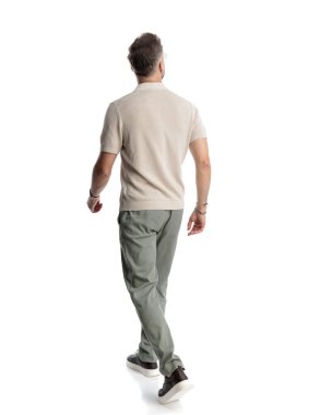 Sıradan bir genç adamın beyaz arka planda yürümesi ve yan tarafa bakması.