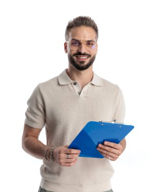 Gözlüklü, pano tutan ve beyaz arka planda gülümseyen sıradan bir genç portresi.