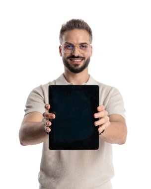 Siyah boş tablet ekranı gösteren gözlüklü gururlu sıradan bir adam ve beyaz arka planda gülümsüyor.