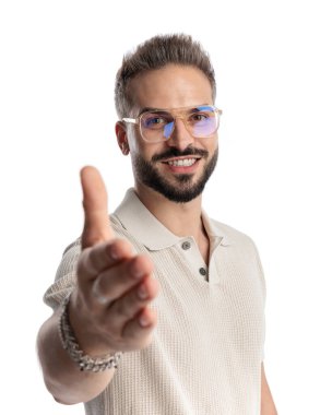 Gözlüklü yakışıklı adam gülümsüyor ve beyaz arka planda güzel bir tokalaşma için el sıkışıyor.