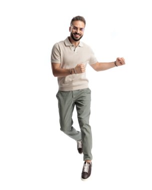 gözlüklü dinamik adam havaya zıplıyor ve beyaz arka planda gülümserken yumruklarını yana doğru hareket ettiriyor.