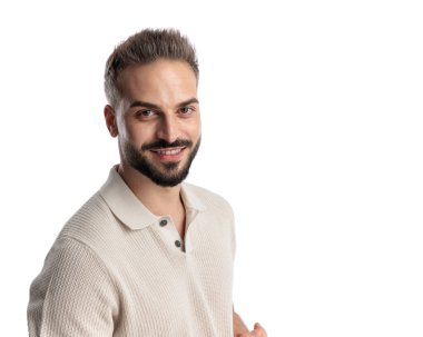 Polo tişörtlü yakışıklı bir gencin portresi. Beyaz arka planda dikilirken ileriye bakıyor ve gülümsüyor.