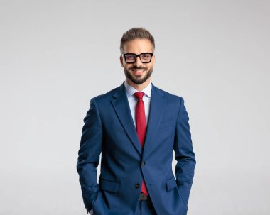 Donanma mavisi takım elbiseli, mutlu, olgun bir iş adamı. Gri arka planda el ele tutuşup gülümsüyor.