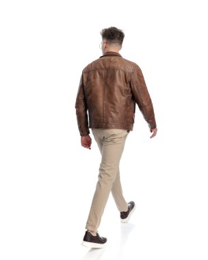 Kahverengi deri ceketli sıradan bir genç adam beyaz arka planda yürüyor.