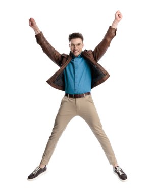 Gözlüklü heyecanlı genç adam havalanıyor ve beyaz arka planda en sevdiği takım için tezahürat yapıyor.