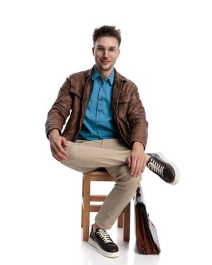 Diz çöküp, beyaz arka planda oturup gülümseyen sıradan bir adam.