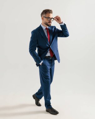 Lacivert takım elbiseli zarif genç işadamı el ele yürüyor ve gri arka planda camları tamir ediyor.