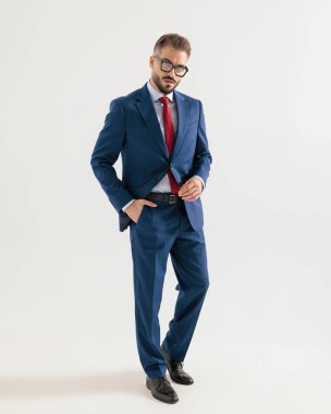 Donanma mavisi takım elbiseli havalı zarif bir adamın el ele yürüdüğü ve gri arka planda ileriye baktığı uzun bir resim.