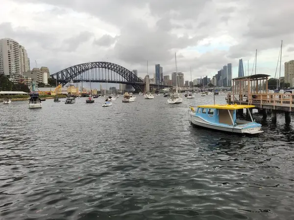 シドニーの港は 曇り空の日に有名なシドニーハーバーブリッジに設定されています ロイヤリティフリーのストック画像