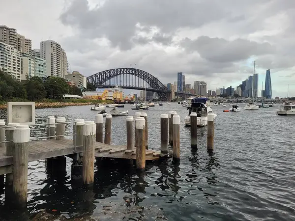 シドニーの港は 曇り空の日に有名なシドニーハーバーブリッジに設定されています ストック写真