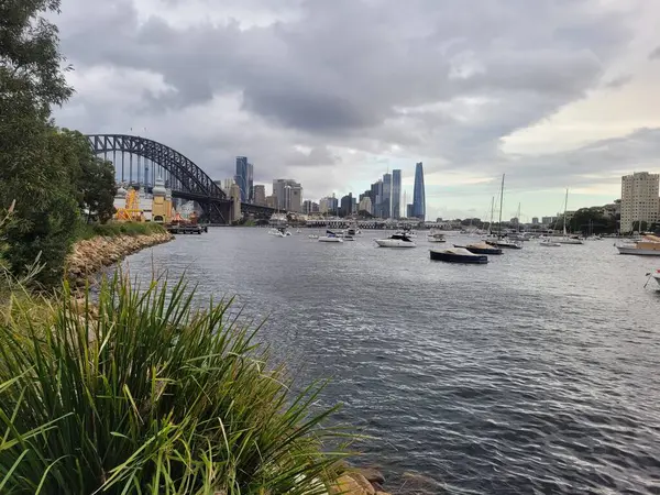 シドニーの港は 曇り空の日に有名なシドニーハーバーブリッジに設定されています ストック画像