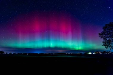 Kuzey ışıklarının kır yolunda dans edişinin manzarası