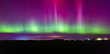 Kuzey ışıklarının bulutlu gökyüzünde dans edişinin manzarası