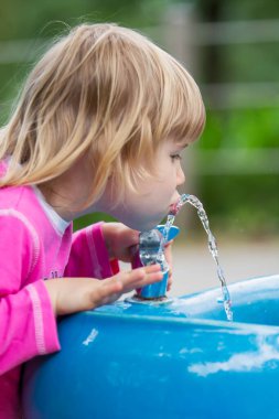 Young child drink water from public fountain