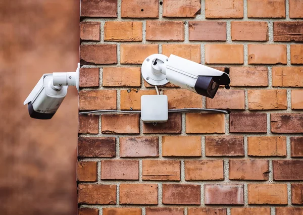 Group of security cameras on red brick wall