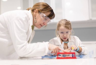 Genç öğrenci okulda öğretmeninin yardımıyla laboratuvarda çalışıyor.